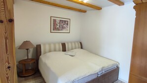 A bedroom with a bed, a nightstand, a lamp, and a framed picture on the wall. - Ferienwohnung Direkt am See (Wokuhl-Dabelow)
