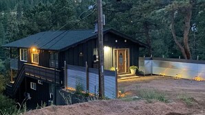 Une cabane à deux étages dotée d’un balcon, d’une porte en bois et d’un petit espace porche.