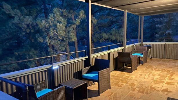 Une terrasse extérieure avec des meubles en osier et une vue sur les arbres.