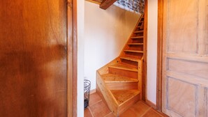 Un escalier en bois mène à une porte surmontée d’un mur en pierre.