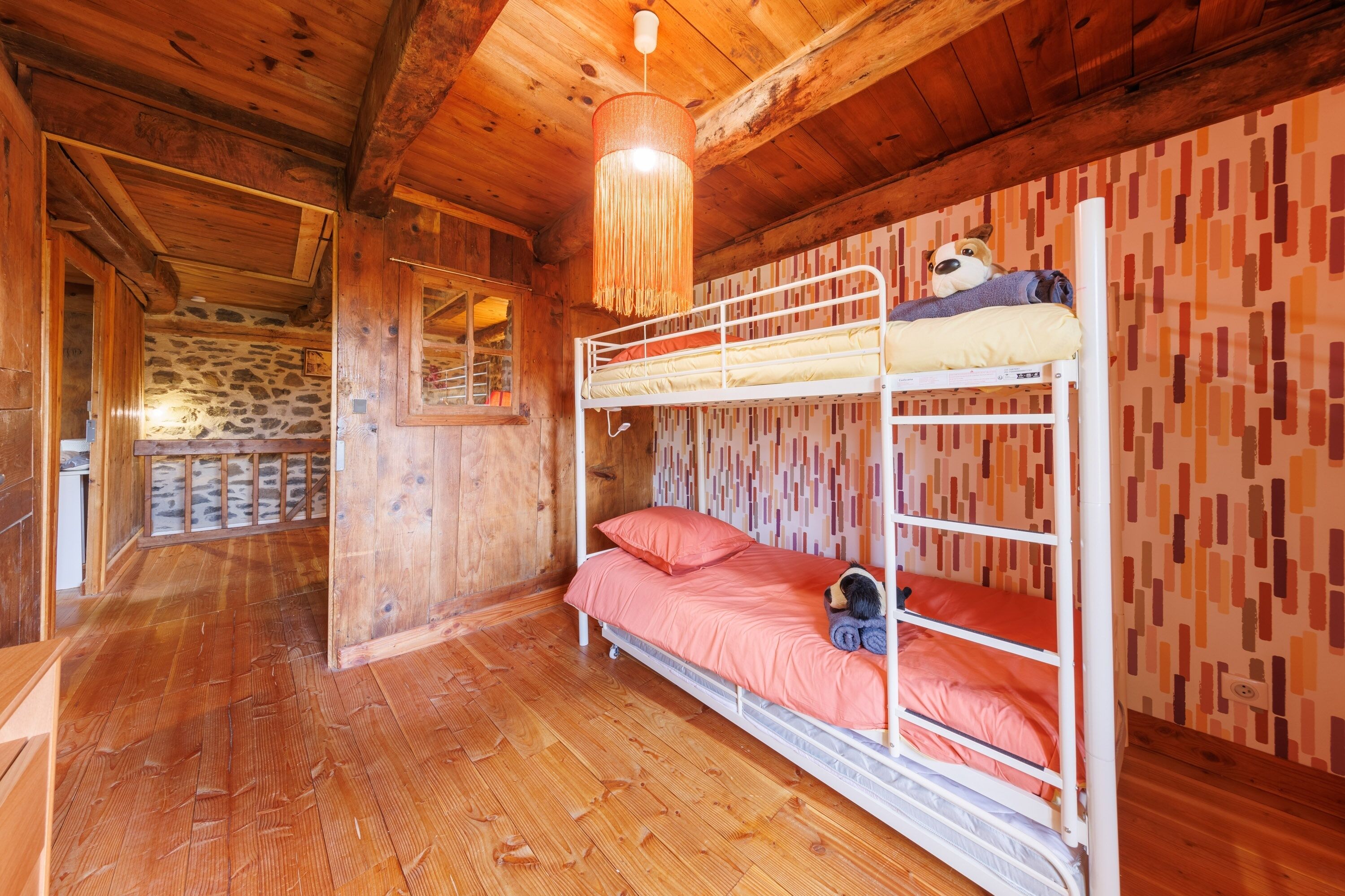 Een slaapkamer met stapelbedden, houten wanden en een stenen muur op de achtergrond.