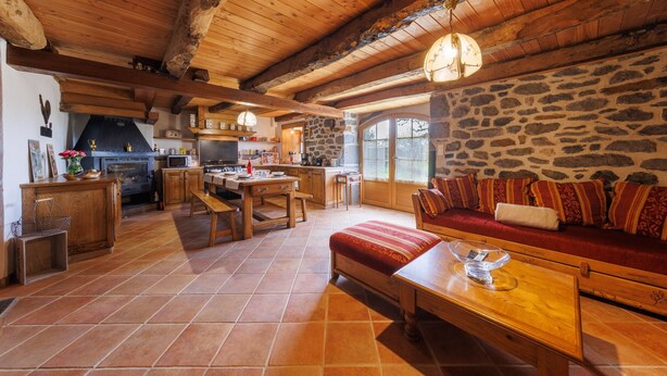 Un intérieur rustique avec un mur en pierre, des meubles en bois et une cheminée en pierre.
