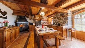 Une cuisine rustique avec des poutres en bois, un mur en pierre et un grand îlot central.