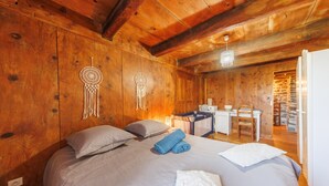 Une chambre à coucher dans une cabane en bois, avec un lit, deux attrape-rêves, un bureau et une chaise.