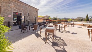 Un patio al aire libre con paredes de piedra, mesas y sillas.
