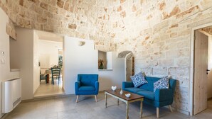 A living room with a stone wall, a blue sofa, a wooden coffee table, and a blue armchair.