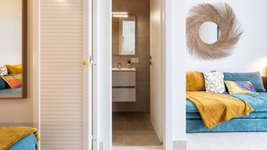 Un dormitorio moderno con una cama grande, una mesita de noche y un espejo fijado a la pared.