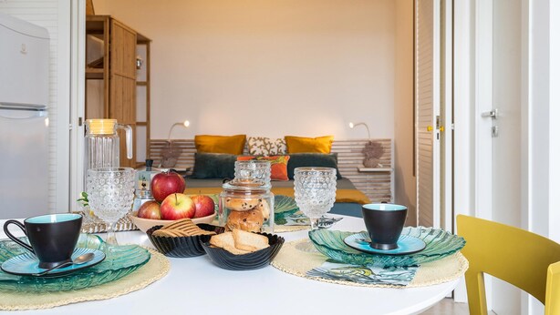 Mesa con vajilla, platos y un cuenco de frutas y galletas.