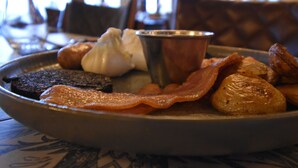 Un plato de desayuno con tocino, huevos y papas.
