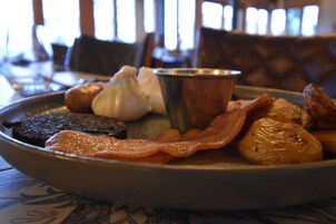 A breakfast plate with bacon, eggs, and potatoes.