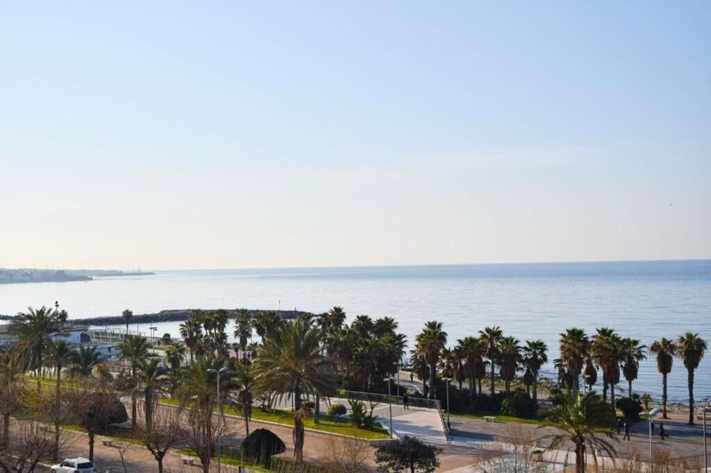 Eine Küstenpromenade mit Palmen, blauem Himmel und Blick auf das Meer.