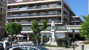 Un edificio de varios pisos con balcones, una estatua en la fachada y el cartel de Banca di Napoli.