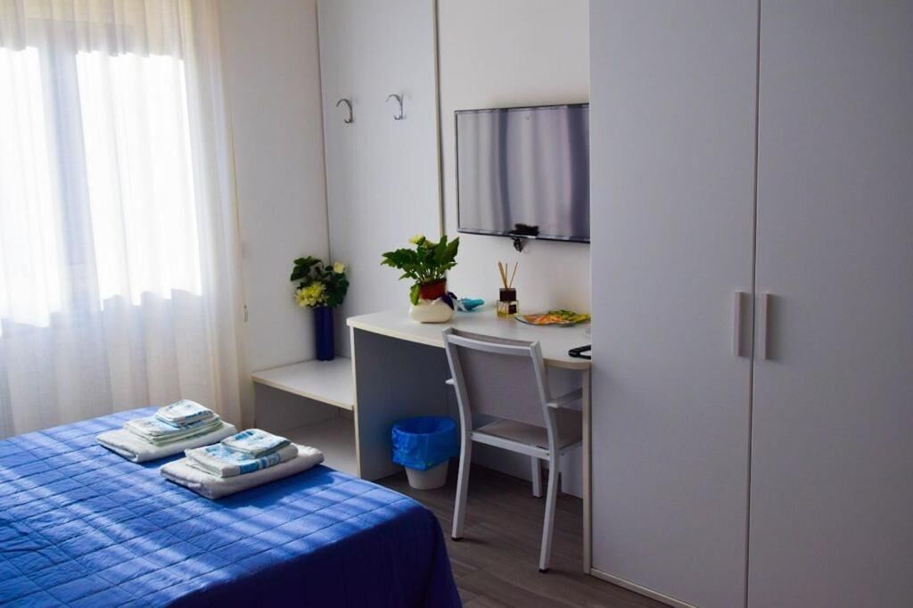 Une chambre d’hôtel comprenant un lit, un bureau, une chaise, une télévision et une armoire.