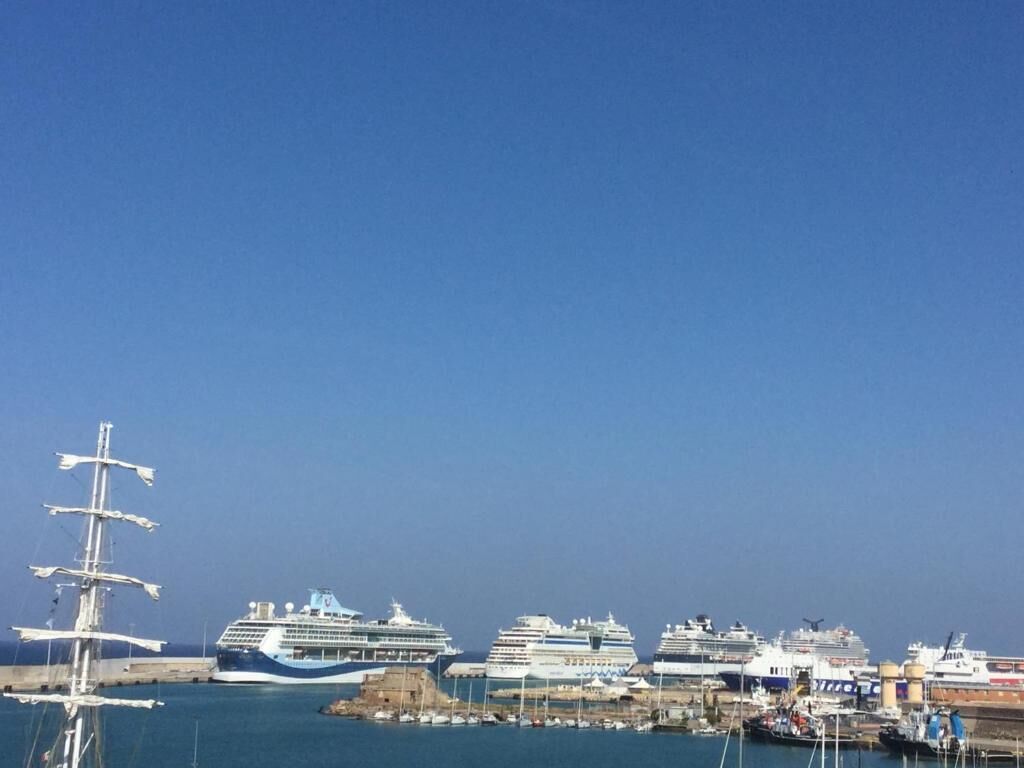 Ein Hafen mit mehreren vor Anker liegenden Kreuzfahrtschiffen.