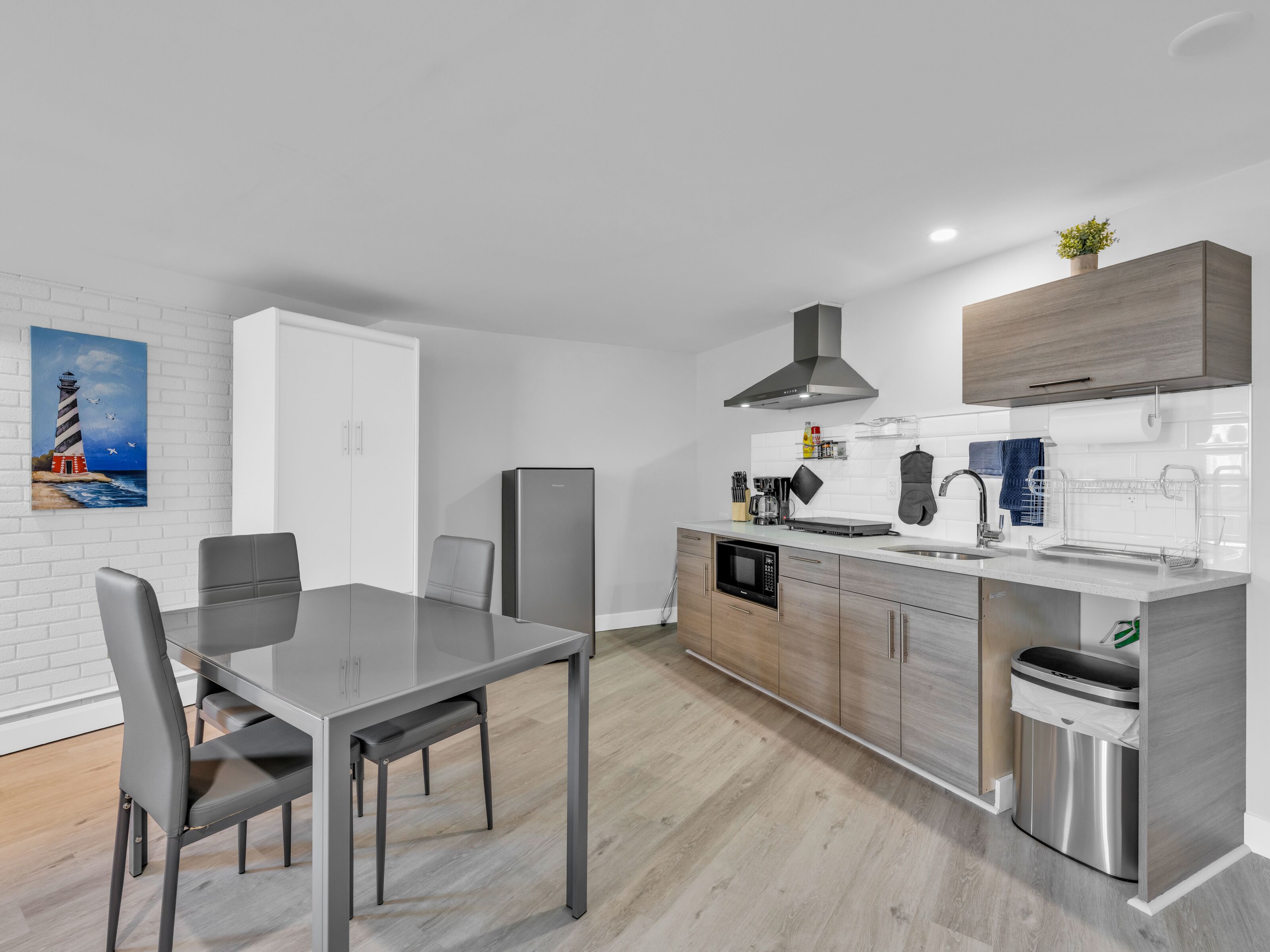 A modern kitchen with a dining area, featuring a stainless steel refrigerator, microwave, and sink.
