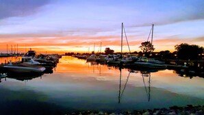 A marina with boats docked at calm waters reflecting the sunset sky.