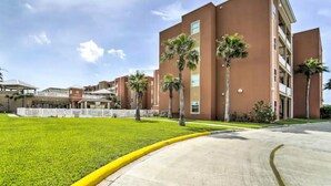 A modern building with a flat roof, multiple floors, and a central courtyard with palm trees. - Coral Cave Luxury Condo! Enjoy the beach, pools, BBQs, and bay views.  (South Padre Island)