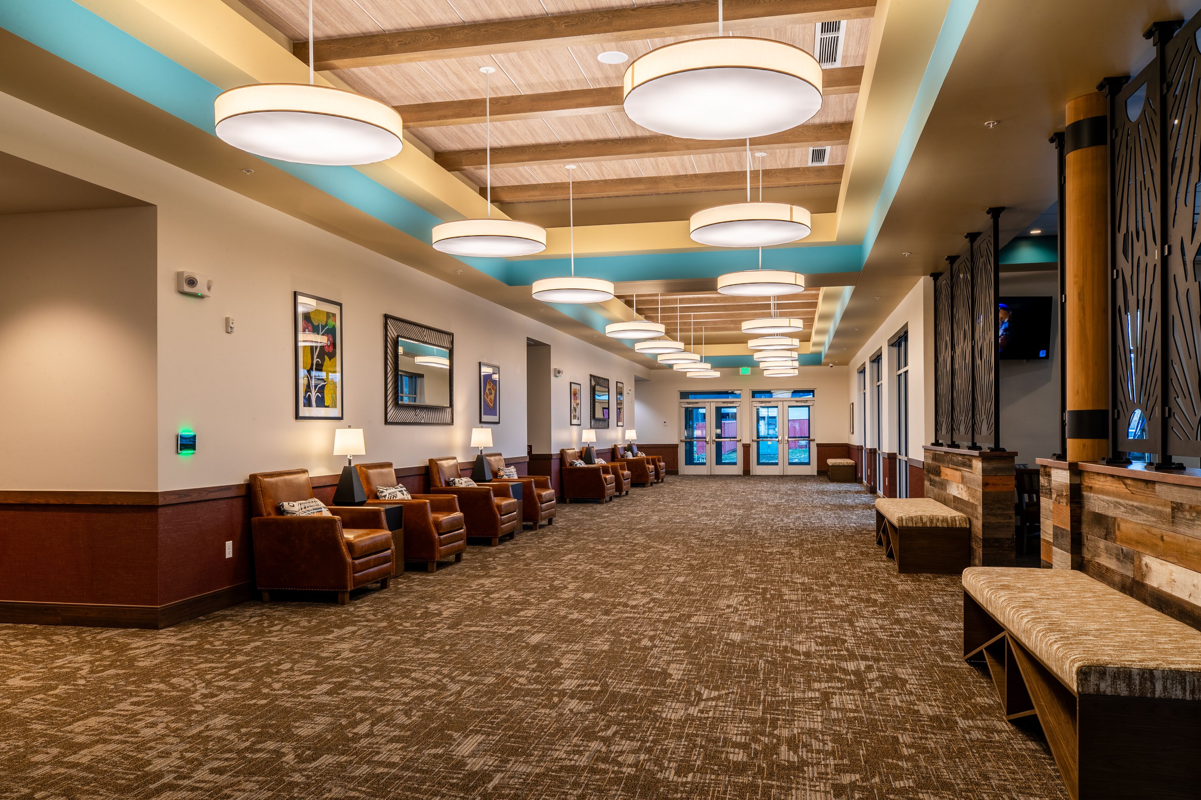 A hotel lobby with a long reception desk, multiple seating areas, and a patterned carpet.