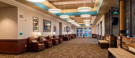 A hotel lobby with a long reception desk, multiple seating areas, and a patterned carpet.