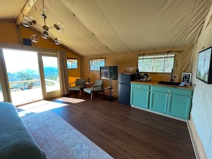 A tented accommodation with a kitchen area, a dining table, and a sofa. - NEW* “Wild Hare” Luxury Glamping Tent for 2 (Townsend)