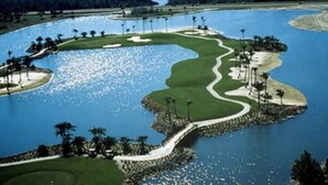 Ein Golfplatz mit Wasserschutzhindernissen, Sandbunkern und Palmen.