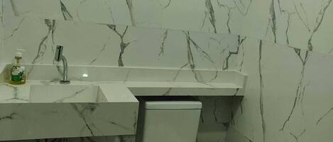 A bathroom with white marble walls and a white toilet.