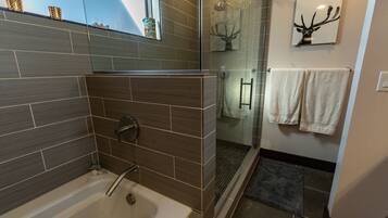 Un baño moderno con bañera, ducha y puerta de cristal.