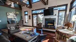 A spacious living room with a fireplace, large windows with mountain views, and modern furnishings. - Pearl Penthouse by Jackson Vacations (Jackson)