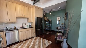 A modern kitchen with wooden cabinets, stainless steel appliances, and a striped rug. - Pearl Penthouse by Jackson Vacations (Jackson)