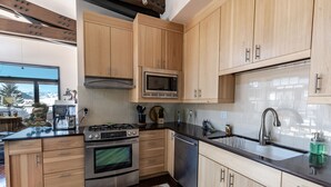 A modern kitchen with wooden cabinets, stainless steel appliances, and a large window. - Pearl Penthouse by Jackson Vacations (Jackson)