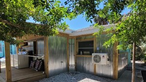 A covered outdoor area with a wooden deck, a seating area, and a small kitchenette.