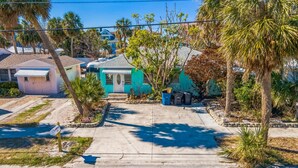 A residential street with houses, including a turquoise house with a front yard and a mailbox.