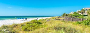 Une plage avec une promenade en bois, des parasols et un ciel dégagé.