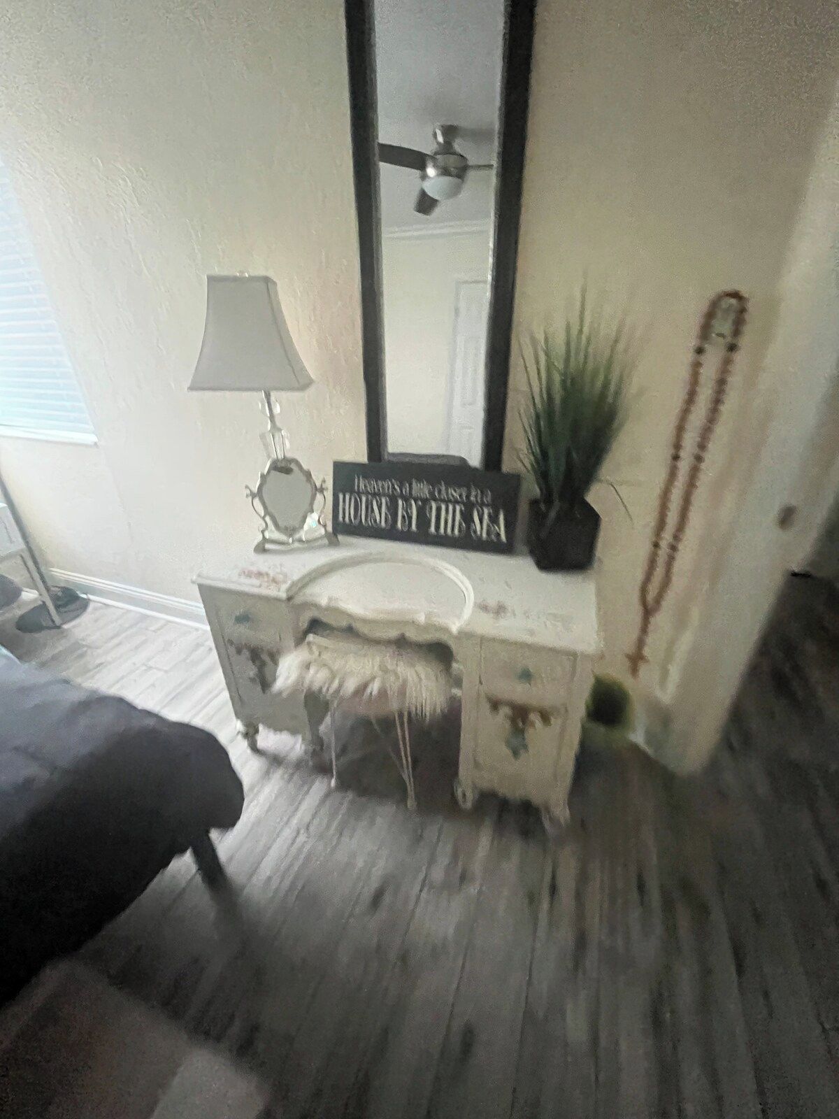 A bathroom with a vanity, a mirror, a ceiling fan, and a sign that reads 'Heaven's little house by the sea.'