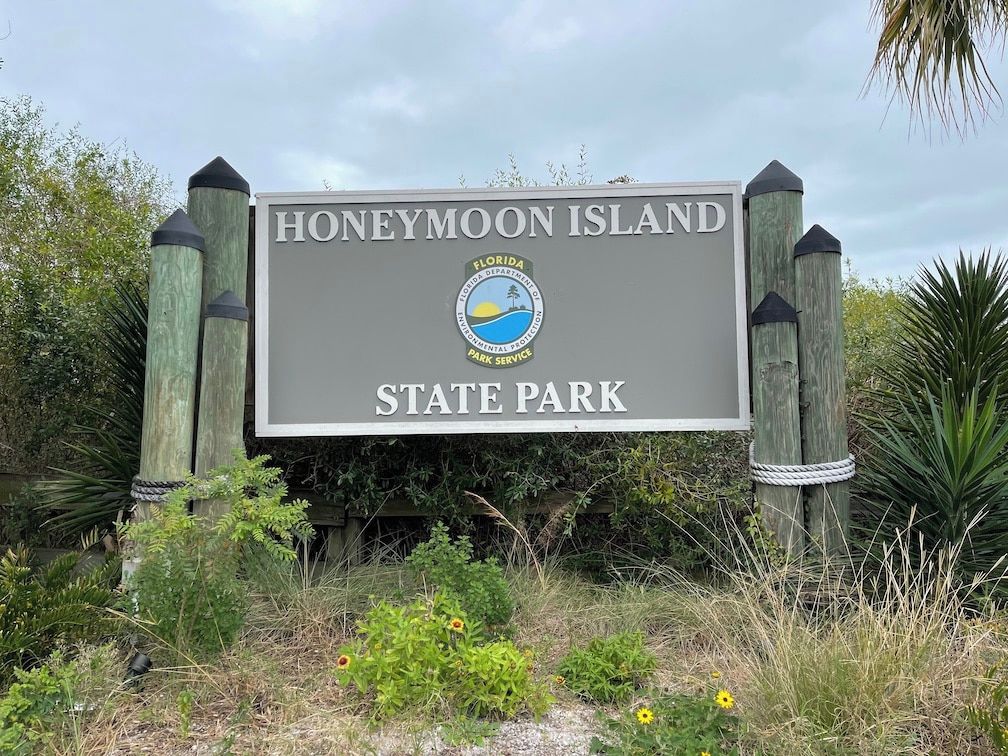 Een bord voor Honeymoon Island State Park, met een logo en tekst.