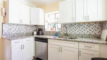 A kitchen with white cabinets, a granite countertop, and a dishwasher.