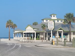 A beachfront restaurant with a patio, outdoor seating, and a view of the ocean.