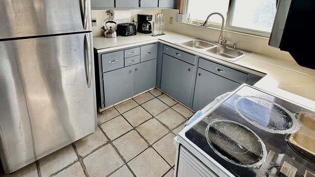 Una cocina compacta con refrigerador, estufa y ventana con vista a árboles.
