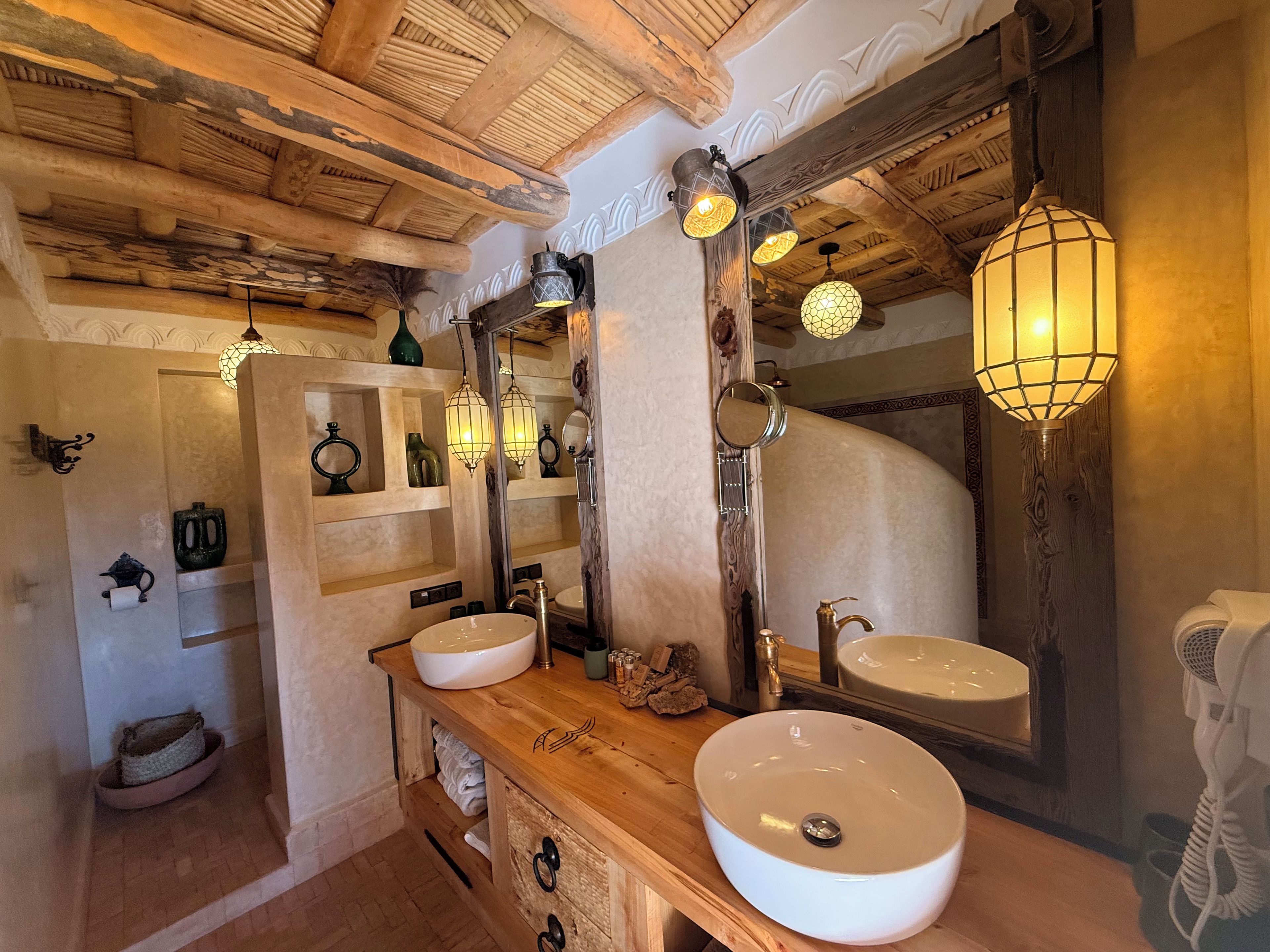 A bathroom with wooden beams, two sinks, a mirror, and decorative lighting.