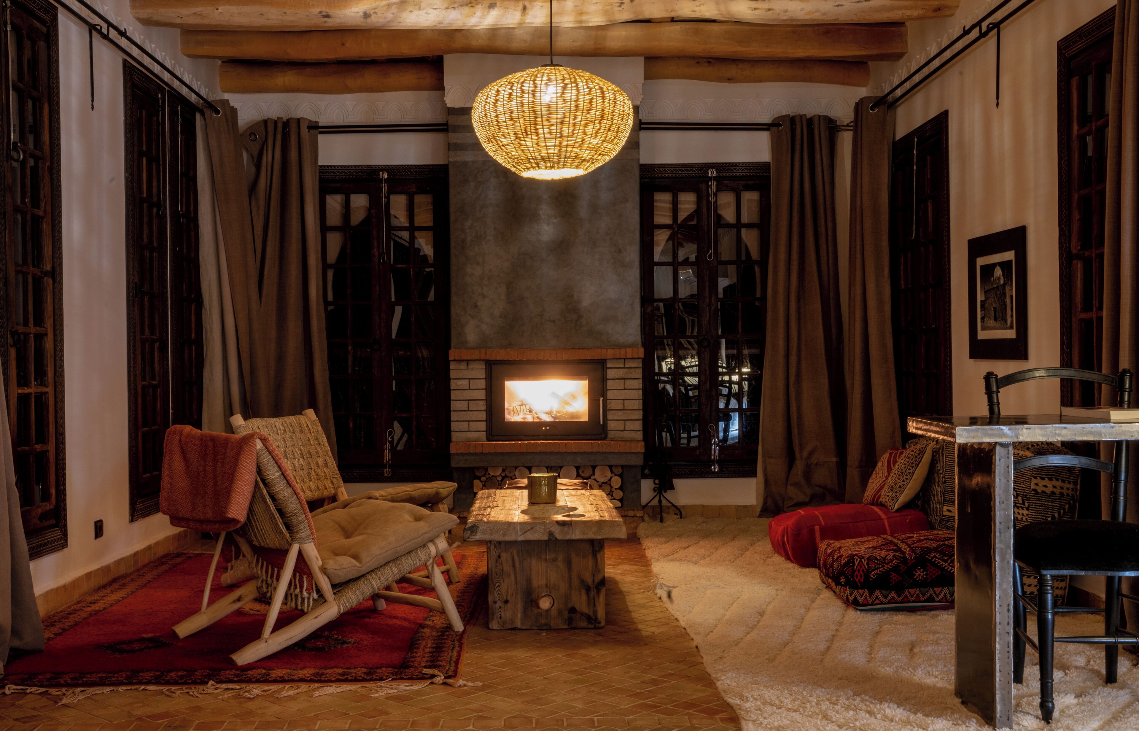 A cozy living room with a fireplace, wooden furniture, and a hanging light fixture.