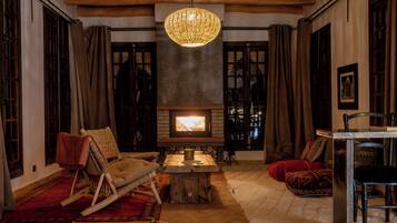 A cozy living room with a fireplace, wooden furniture, and a hanging light fixture.