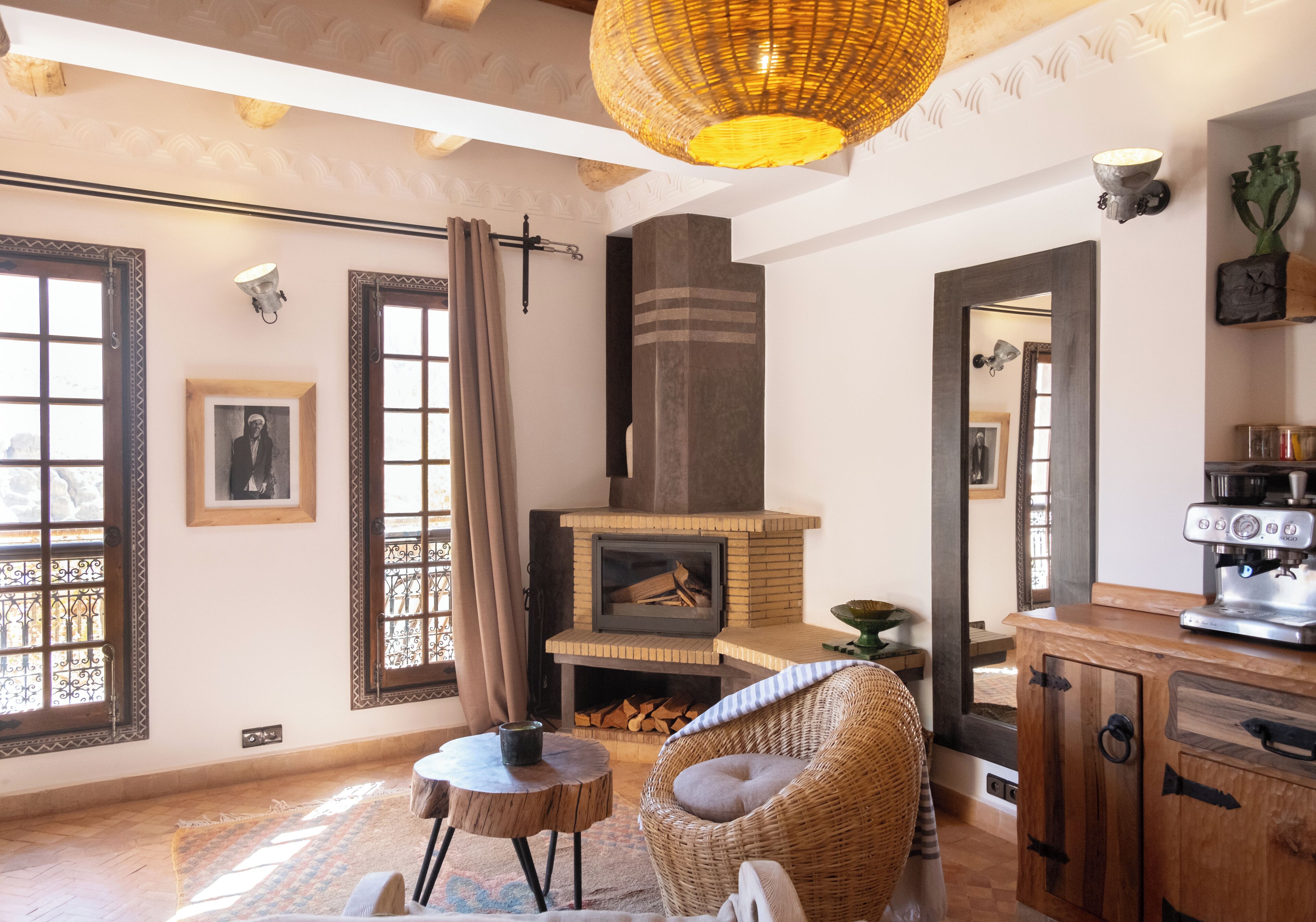 Una sala de estar acogedora con chimenea, muebles de mimbre y una máquina de café.