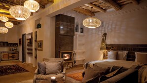 A cozy room with a fireplace, a sofa, a chair, and a dining table. - Eden Boutique Hotel (Ait Sedrate Jbel El Soufla)