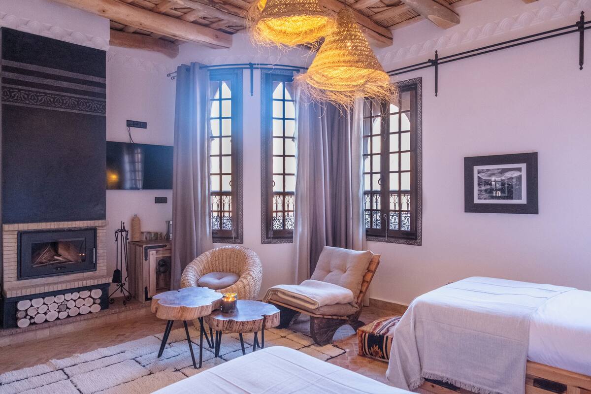 A cozy room with a fireplace, wicker furniture, and a bed.