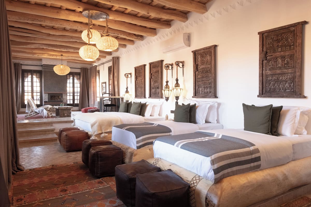A hotel room with two beds, a fireplace, and decorative wall art.