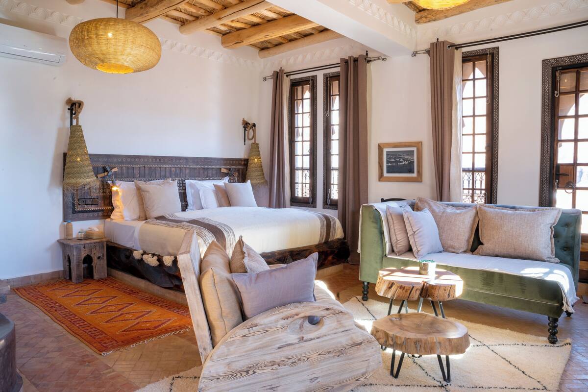 A traditional room with a bed, a sofa, a wooden coffee table, and a patterned rug.