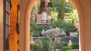 An arched doorway leading to a garden with a variety of plants and a hanging light fixture. - Eden Boutique Hotel (Ait Sedrate Jbel El Soufla)