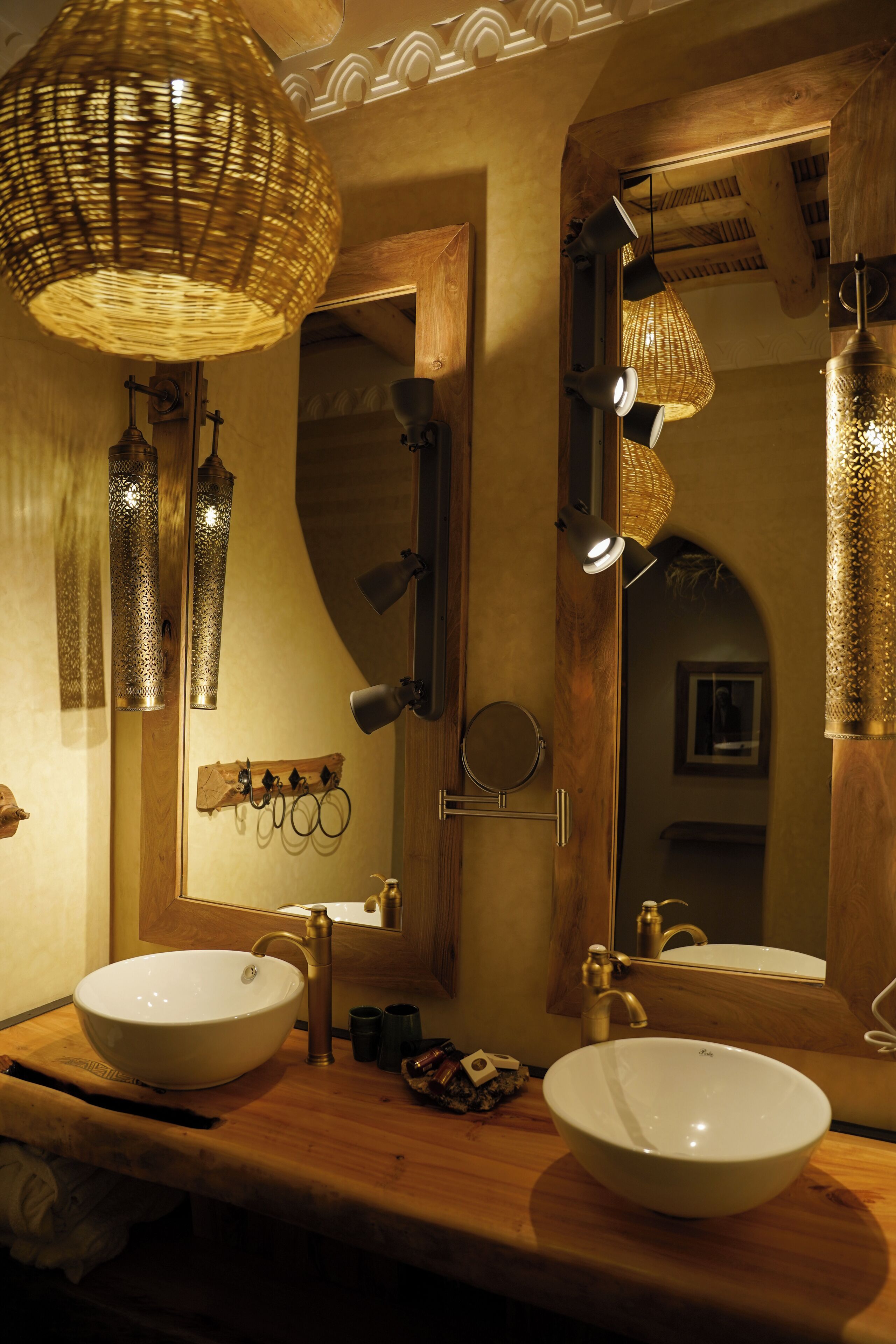 Un baño con dos lavabos, un espejo e iluminación decorativa.