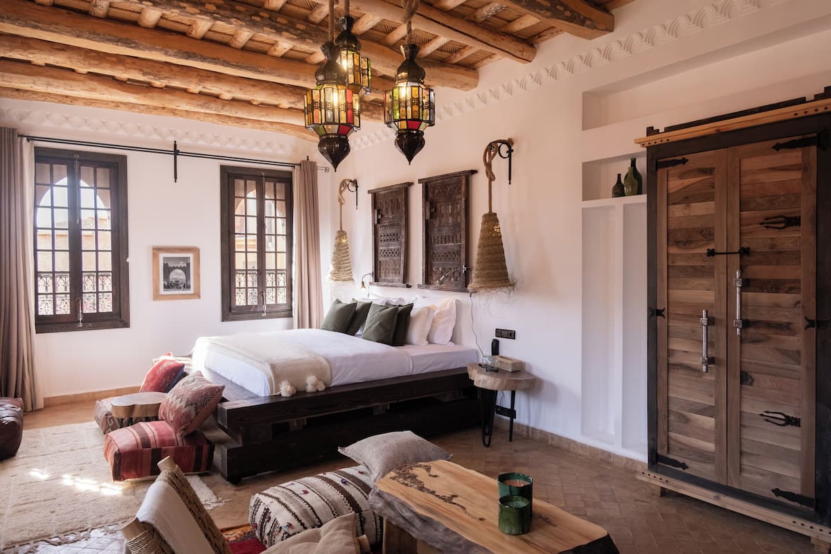A cozy bedroom with a wooden bed, a small table, and a wardrobe.