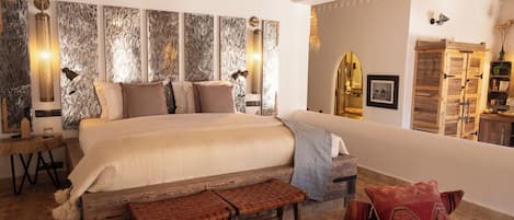 A spacious bedroom with a large bed, a wooden bench, and a small table.
